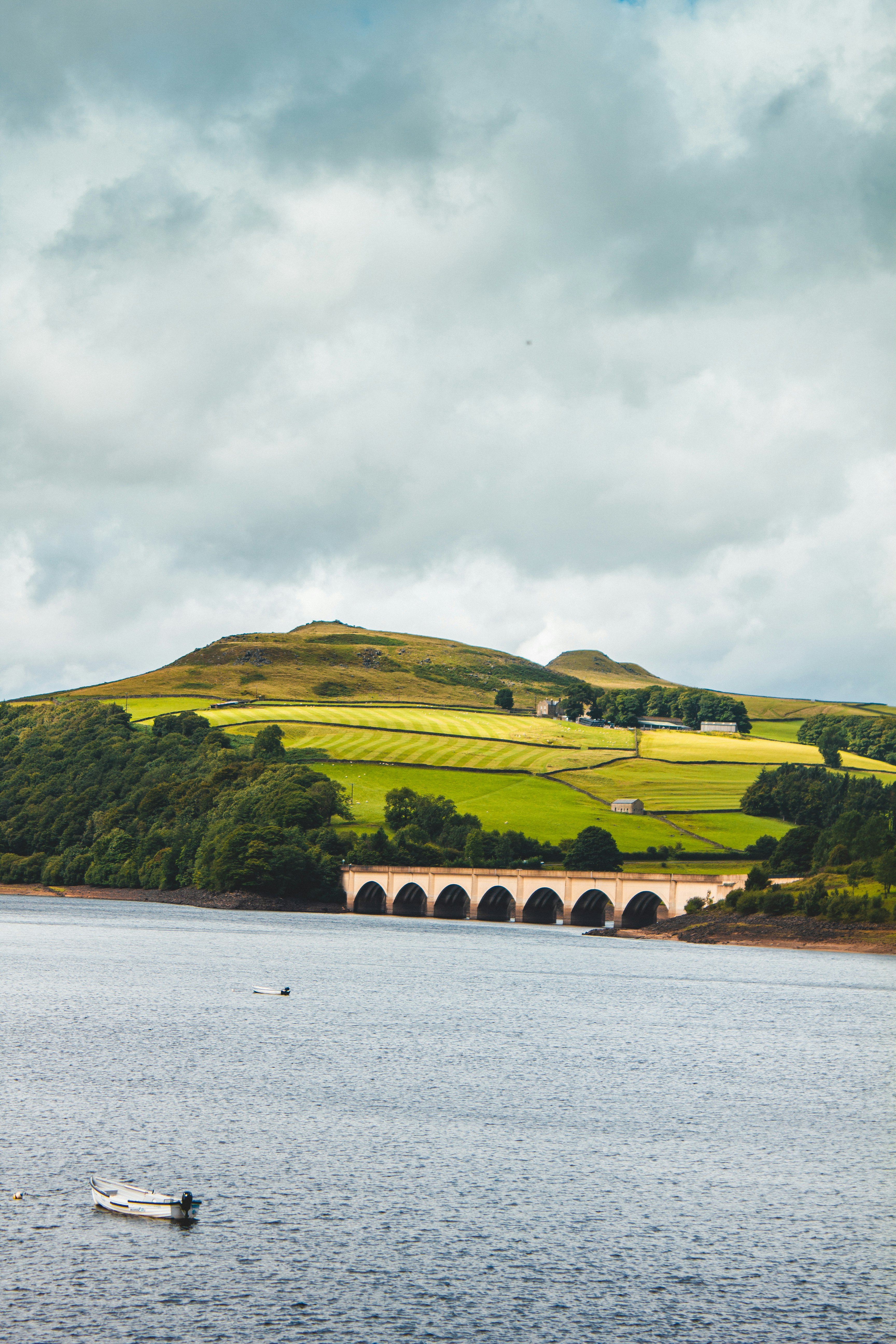 green mountain beside body of water under cloudy sky during daytime